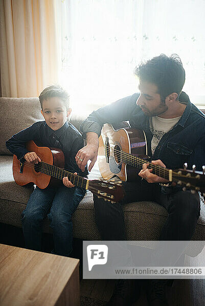 Daddy with son playing accoustic guitar.