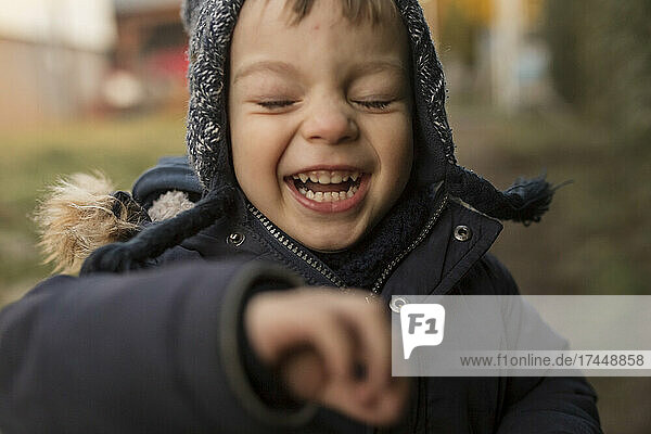 Laughing and running toddler boy in warm clothes in backyard