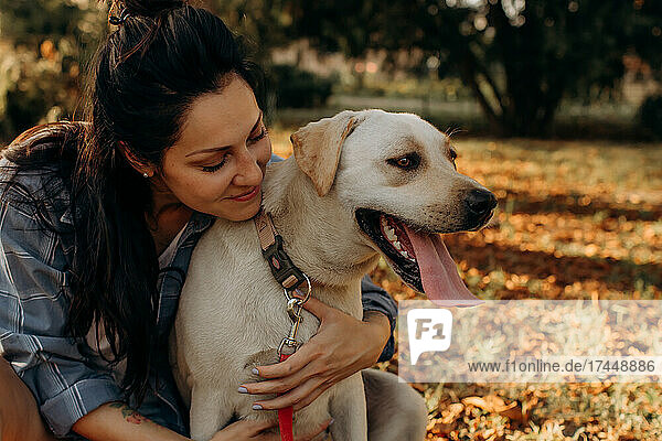 Happy woman hugging her Labrador puppy outdoors