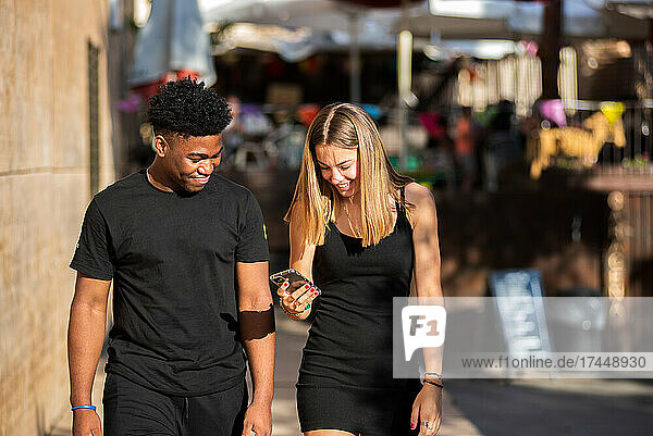 Young black boy and blonde Caucasian girl walking in the city.