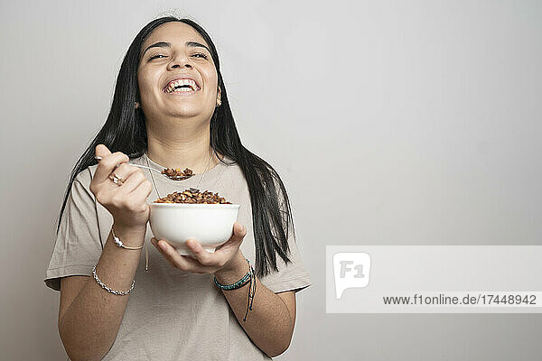 Portrait of a woman laughing while eating a bowl of granola