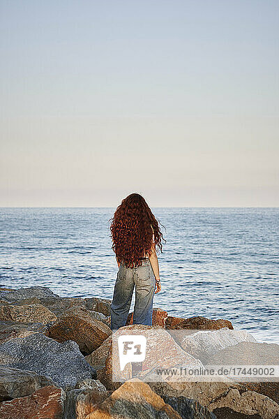 Young redhead woman on her back looks to the sea