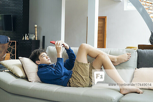 The boy playing online game on smartphone at home