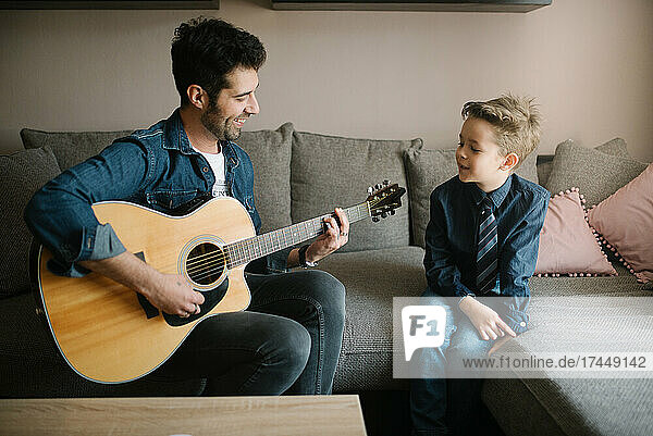 A father playing guitar to his son.