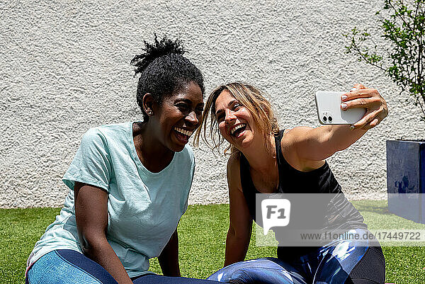 Laughing multiethnic women in sportswear taking selfie