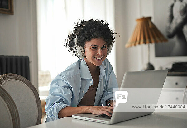 smiling young woman works with computer at home
