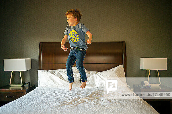 Happy boy jumping on a hotel bed