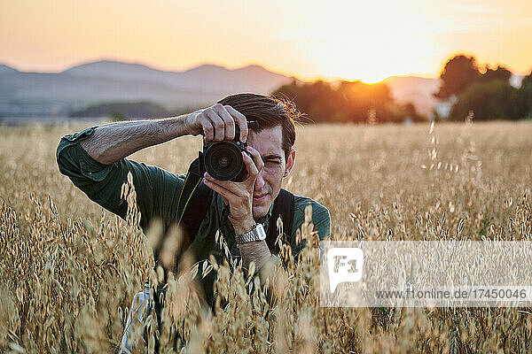 Portrait of a photographer looking at camera in a meadow at sunset