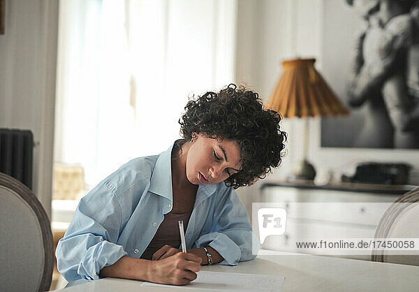 young woman writes on paper with pen at home