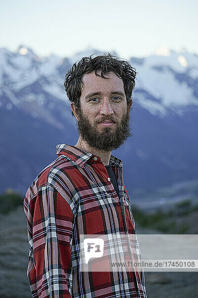 Young male adult with red lumberjack shirt in the mountains