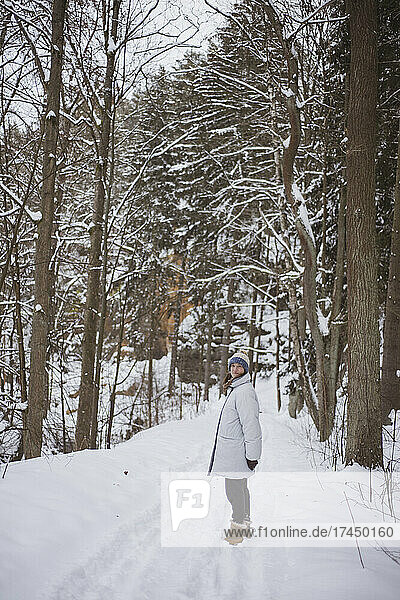 smiling woman stands along in beautiful snow covered Czech forrest