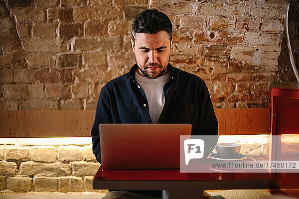 Concentrated businessman using laptop computer at cafe