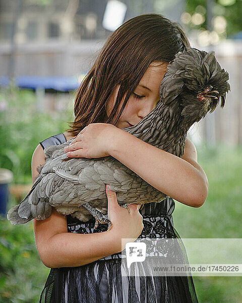 Beautiful girl  eyes closed  tenderly holds a pet chicken in her arms