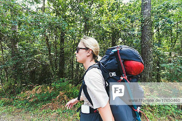 pilgrim woman doing the portuguese way with backpack against forest