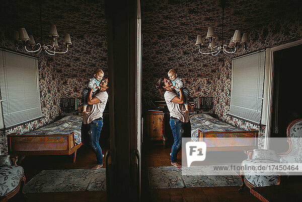 Mom holding baby up in vintage room with mirror reflection