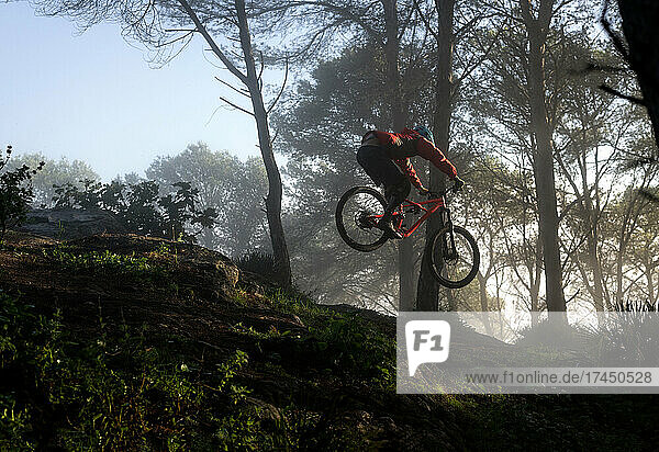 Young mountain biker jumps in a nice foggy morning