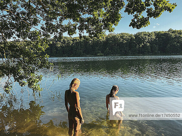 two beautiful natural women stand nude in green lake in europe