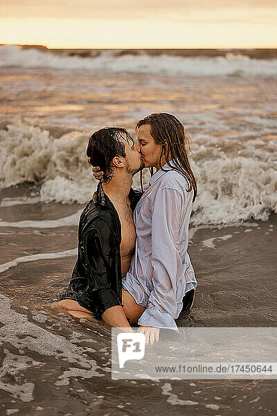 young couple kissing in the ocean