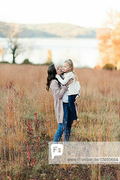 Mother and daughter hugging in a field of tall red grass