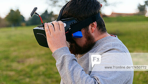 Man holding his virtual reality goggles to fly his fpv drone.