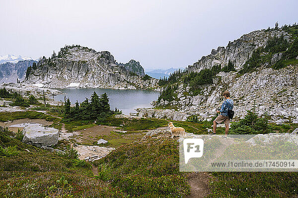 Hiker taking photo of his dog at an alpine lake in the north cascades