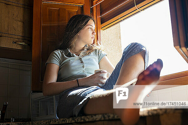 Teenage woman sitting looking out the window