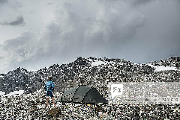 A boy looks over a tent after a storm in Glacier Peak Wilderness area.
