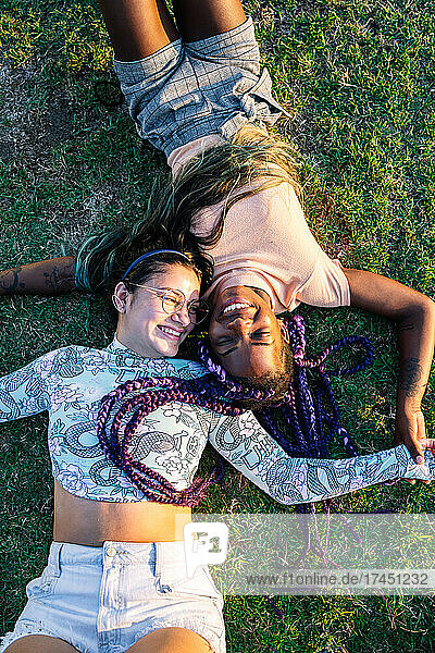 Multiracial female couple lying on the grass. Lesbian couple