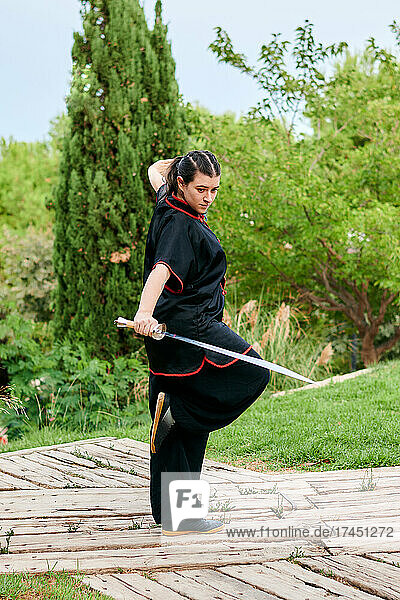 Woman training kung fu with a sword in a park