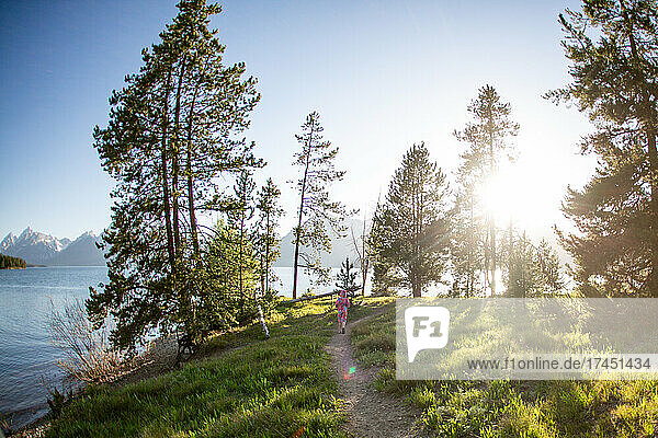 Young girl running down a trail on a sunny day in Grand Tetons