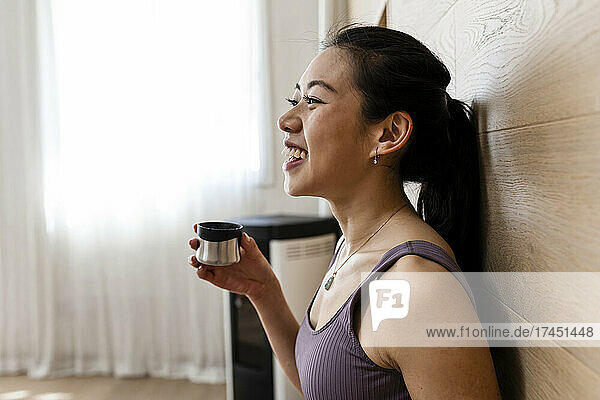 Asian woman in workout tight suit is holding yoga tea before workout