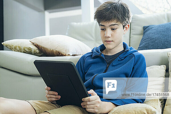 The boy using tablet at home.