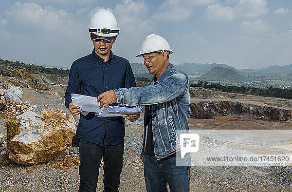 engineers discussing survey plan at gravel mine in Thailand