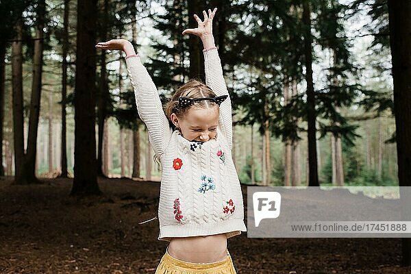 girl throwing twigs up in the air in a forest in autumn