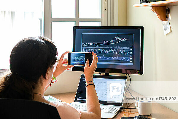 Female trader shooting stock graphs while working from home.