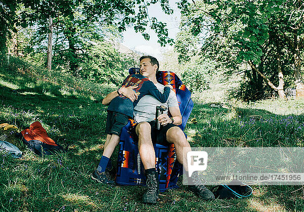 dad hugging his son whilst camping in the sunshine on vacation