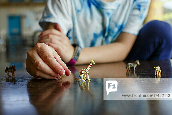 close-up of little girl playing with miniature toy animals on tabletop