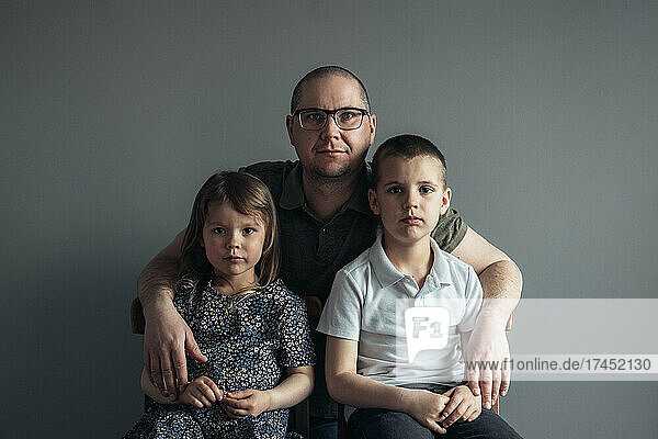 Portrait of father and children on the grey background at home.