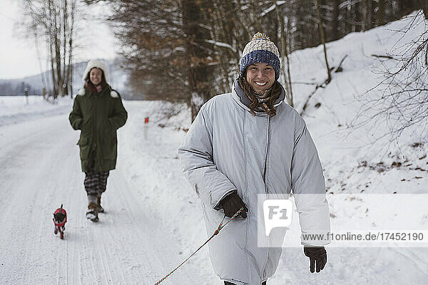 Happy women walk dogs in white snow road smiling in winter in czechia
