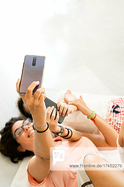 Mother and girl lying on floor taking a selfie and having fun at home