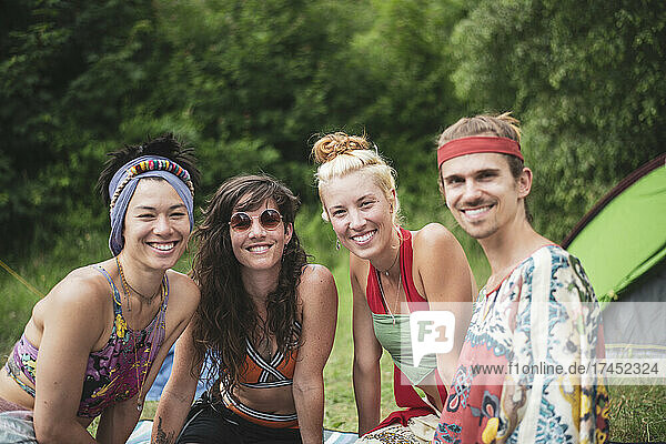Colourful group of queer friends smile at festival camp in nature