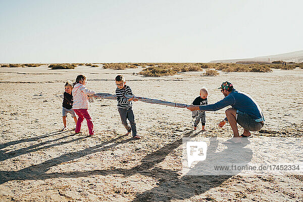 Siblings and parent playing at the beach at sunset in Canary Islands