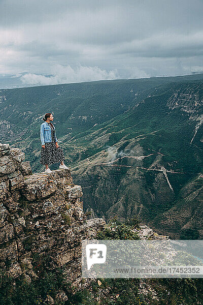 A traveling woman stands on the edge of a mountain cliff and watching