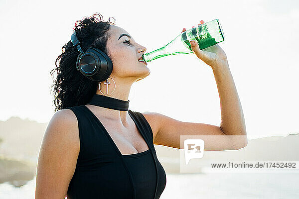 Young pretty caucasian girl drinking beer and listening to music