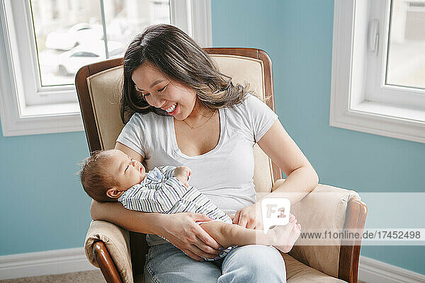 Proud smiling Chinese Asian mother holding newborn baby boy