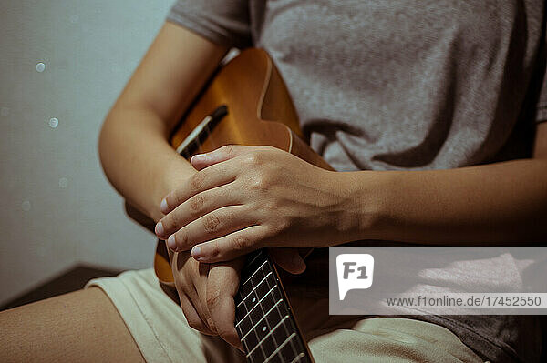 Girl's hands folded on wooden ukulele  close-up