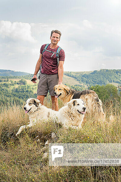 Adult man hiking in nature with shepherd dogs  on the hills in s