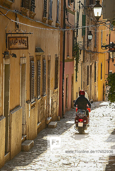 woman riding scooter through narrow street in Rovinj