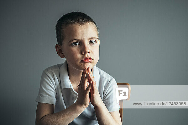 Portrait of little pensive boy sitting on the chair.