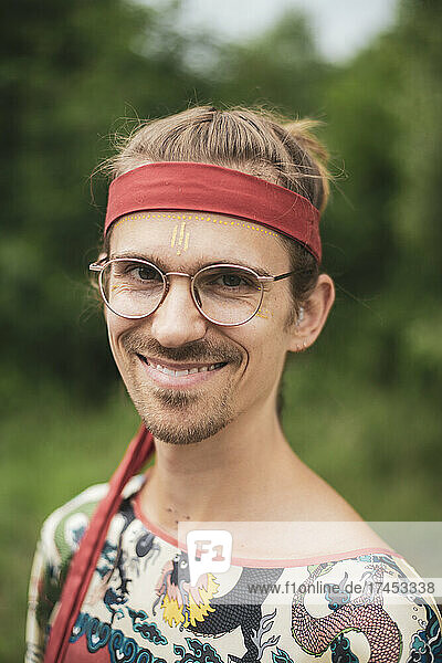 happy man at festival with glasses  facepaint and red bandana